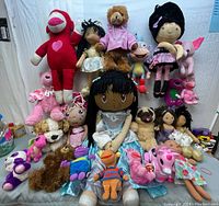 Front view of lot showing large red sock monkey, fabric dolls, assorted plush animals on grey surface against white background