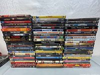Stack of DVD movies including action, thriller, and animation films.