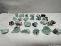 Front view of the lot showing all Amazonite stones laid out on a white cloth with a neutral background.