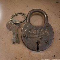 Front view of vintage Corbin padlock showing embossed brand name and attached key on keyring.