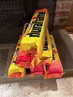 Six Duraflame firelogs wrapped in branded yellow and red packaging stacked on a hearth in front of a fireplace.