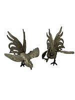 Two metal rooster figurines posed in fighting stances, showing detail of wings and tail feathers, approximating 5 by 4.5 inches each.