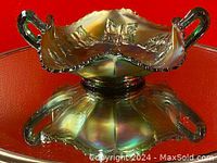 Side view of the green carnival glass bonbon dish showing ruffled edges and butterfly-shaped handles.