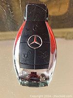 Front view of the Mercedes Benz key fob style lighter showing black plastic buttons, Mercedes emblem, and chrome base.