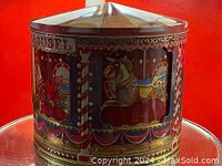 Front and side views of the carousel biscuit tin showing the rotating horses and decorations.