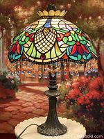 Full view of lamp showing stained glass shade, fringe and metal base