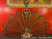 Open fan configuration showing ten radiating pierced brass panels forming a peacock tail shape.