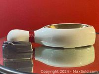 Side view of the white and red hand painted bowling pin ashtray next to the metallic Ronson lighter showing size comparison.