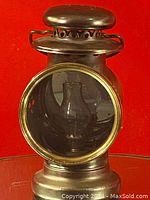 Front view of the vintage metal lantern showing the glass chimney inside through the glass window.