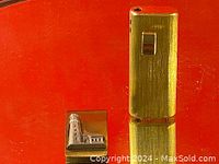 Photo showing close-up of lighter and lighthouse money clip on red background.