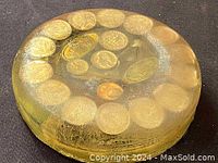 Top side view showing circular arrangement of vintage coins embedded inside clear material.