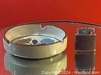 Photo of vintage round pottery ashtray with painted floral/leaf designs and notches for holding cigarettes.