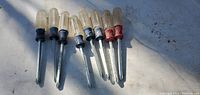 Photo showing 8 vintage screwdrivers with translucent yellow handles and blue and red caps, laid out on a white surface under sunlight.