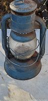 Full view of blue vintage metal lantern with glass dome showing rust and wear.