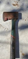 Full view of vintage hatchet with green handle and metal head showing wear and rust.