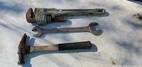 Photo showing a Kobalt pipe wrench, a double open-end wrench, and a hammer with worn handles and some rust.