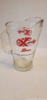 Full view of the large glass pitcher with handle and Lucky Beer logo in red.