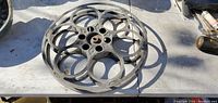 Photo of one 13-inch vintage metal film reel showing circular cutouts and mounting hole, placed on a table outdoors.