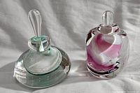 Two vintage signed perfume bottles: one with turquoise swirl and teardrop stopper, one pink and white swirl with rounded stopper