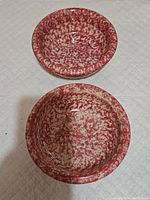 Overhead view of two round pink spongeware bowls with speckled pattern.