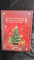 Box showing item branding and description as Retro Ceramic Light-up Christmas Tree with Multi-Colored Light Bulbs by Sunlit.