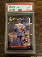 Front view of 1987 Leaf Reggie Jackson baseball card in PSA case showing player batting pose and card details.