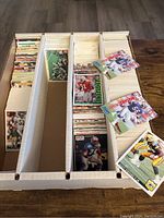 Box divider filled with rows of football trading cards, some loose cards shown on top including special insert cards.