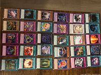 Photo shows 40 YuGiOh! cards laid out in rows on a flat surface, including monsters, spells, and trap cards with various colorful illustrations.
