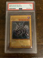 Front view of the 2003 YuGiOh! SDJ-001 Red-Eyes Black Dragon card graded PSA 7 in protective case, showing card details and artwork.
