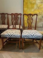Group view of five mahogany chairs showing carved backs and upholstered seats