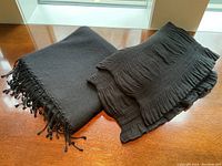 Both scarves folded side by side on wooden surface