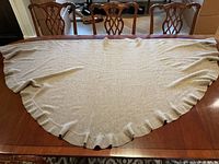 Full view of beige cashmere shawl laid flat displaying its semi-circular shape with ruffled edge detail