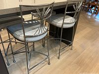 Two bar stools viewed at an angle on hardwood floor showing pewter finish and striped seats