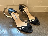 Pair of black open-toe Manolo Blahnik heels showing left and right shoes placed side by side from an angled front view.