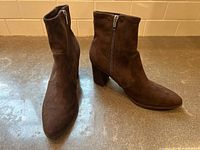 Pair of brown suede ankle boots shown side by side, highlighting side zipper and block heel design.