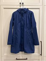 Full front view of the blue hooded Patagonia jacket hanging, showing overall design, length, and pockets.