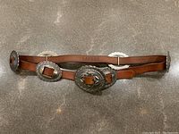 Overall view of caramel leather belt showing full length and concho hardware