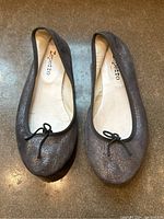 Top-down photo of both ballet flats showing sparkling grey leather and tied bow detail