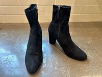 Front view of pair of black suede ankle boots showing overall shape and condition.