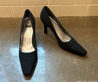 Front side view of both black high heel shoes showing their shape and heel height.
