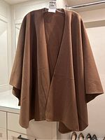 Front view of a brown wool cape hanging, showing the full cape shape and open front design.