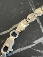 Close-up of lobster clasp end of sterling silver chain with 925 and Italy markings.