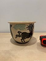 Front view of the vintage ceramic plant pot depicting a black horse and turquoise clouds on beige background.