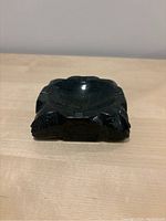 Front and top view showing polished interior and carved face motifs on the sides.