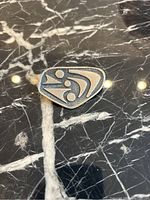 Pewter brooch on black marble surface showing abstract Mid-Century Modern geometric design with circles and lines.