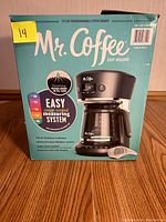 Front package view of Mr. Coffee 12 cup programmable coffee maker in blue packaging highlighting easy color coded measuring system.