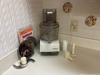 Full view of the assembled food processor with attachments and manual visible on the counter.