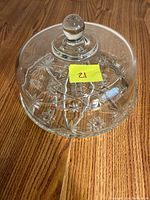 Top view of clear glass cake stand lid with floral etched pattern visible on the base through the glass.