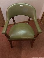Front view of the chair showing curved back, green vinyl upholstery, armrests and wooden frame