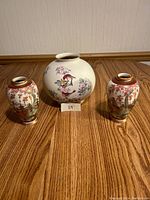 Set of three Japanese vases on wood floor: two narrow neck vases and one large round vase